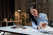 © crizzystudio - Young asian businesswoman working late managing financial documents