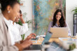 © Studio Marmellata - Three diverse women are working on laptops in a bright office. They are smiling and engaged, creating a positive and collaborative work environment.