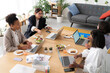 © Studio Marmellata - Four diverse women work on laptops and enjoy a healthy lunch with salads and sandwiches at a bright, modern office table. They collaborate during their meal break.