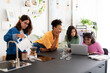 © Studio Marmellata - Four diverse young women are together in a bright kitchen. One makes pour-over coffee as the others focus on a laptop, collaborating and sharing ideas.