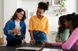 © Studio Marmellata - Four diverse young women gather in a bright kitchen. One woman pours coffee into glasses while her friends watch and smile, enjoying their time together.