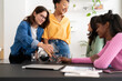 © Studio Marmellata - A group of diverse young women enjoys a casual gathering. One woman serves coffee to her smiling friends, fostering connection and shared happy moments.