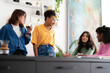 © Studio Marmellata - Four diverse young women are enjoying a casual gathering indoors. They are smiling, talking, and holding drinks, sharing a pleasant moment together.