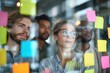 © ttonaorh - Group of young professionals collaborating during brainstorming session, using colorful sticky notes on glass wall in modern office.