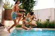 © Valerii Apetroaiei - Group of friends jumping into pool together during fun summer vacation