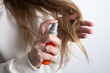 © Iuliia Pilipeichenko - Close-up of woman applying cosmetic spray to hair. Concept of healthy hair, beauty treatment, and self care.