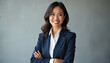 © miss irine - Filipino businesswoman smiles confidently, arms crossed, wearing a dark suit and white shirt. Professional headshot in studio for business and career use. Represents leadership and success.