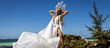 © marcink3333 - Elegant woman in flowing white dress and crown posing by turquoise ocean on Mauritius beach under blue sky, luxury fashion photoshoot with wind and movement