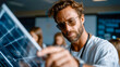 © Aliaksandra - Focused man examining a solar panel indoors, symbolizing renewable energy innovation and modern engineering