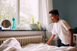 © Maskot - Boy making his own bed in bedroom at home