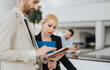 © qunica.com - Two professionals in a corporate lobby examine folders and files, sharing notes and focusing on a project in a bright, modern workspace.