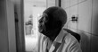 © Marco - One Elderly Afro-descendant man in black and white profile view, gazing upward with a thoughtful and calm expression, seated in a quiet indoor home setting
