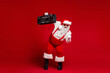 © deagreez - Santa with a retro boombox dances in a red studio creating festive energy for Christmas season and holiday celebration