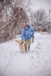 © StockMediaSeller - Elderly woman in a blue jacket walking her happy Golden Retriever on a snowy path. The cheerful dog moves beside her as they enjoy a quiet winter walk surrounded by snow-covered trees.