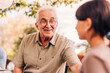 © Maskot - Smiling grandfather talking with granddaughter in back yard at reunion party