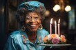 © Margarita Vais  - happy mature african american woman in blue dress holding cake with candles on it. She smiling and she happy