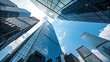 © Visunex - Looking up at the modern skyscrapers in the financial district with blue sky and white clouds, reflecting the sunlight on the glass facade in the city center