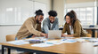 © gankevstock - Joyful diverse team smiling and collaborating on a project with a laptop in a bright modern office