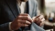© CYBERPINK - Close-up of a man's hands working on a piece of fabric. he is wearing a blue suit jacket and a white shirt.