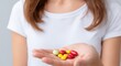 © LimeSky - Close up of a woman in a white t shirt a nutritionist showcasing various colored diet pills and weight loss supplements on her palm against a white background