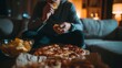 © LimeSky - Nighttime close up of a person snacking on pizza and chips in front of the TV Poor habit