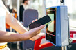 © Koldo_Studio - Woman using mobile payment on a contactless reader inside a public city bus, representing modern travel and technology