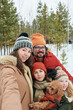 © pressmaster - Portrait of Caucasian man and woman with Caucasian girl and boy standing outdoors in snowy forest smiling at camera, girl and boy wearing winter hats, holding small brown dog