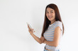 © Suthida - Asian Thai Young Woman Wearing Casual Attire and Smiling Cheerfully While Holding a Smartphone in Her Hand