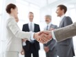 © Uud - Business professionals shaking hands, symbolizing agreement and partnership in an office setting.
