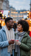 © Milan - Happy black couple smiling at a festive Christmas market. Vertical portrait of a man and woman in love enjoying a warm drink on a winter date
