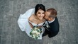 © Imagine  - Romantic newlywed couple embracing on their wedding day, bride in elegant white gown holding bouquet, groom in black suit kissing her cheek, captured from above with love and tenderness