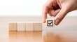 © AnhaJahan - Hand placing a wooden block with a check mark symbol to complete a sequence of blank blocks