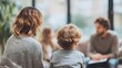© LimeSky - Back view of a female psychologist assisting a young family with child development issues while they sit on a sofa in the blurred background