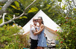 © romaset - A couple of man and woman in front of a tent at glamping.