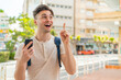 © luismolinero - Young handsome man using mobile phone at outdoors intending to realizes the solution while lifting a finger up