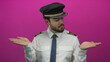 © Krakenimages.com - Young hispanic pilot in uniform extends hands against bright pink background conveying choice and decision in aviation context.