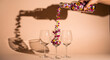 © PoliBegum - Creative concept of colorful confetti pouring from a bottle into champagne flutes casting a shadow