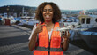 © Krakenimages.com - Woman pointing finger to drone at port marina beside boats wearing orange safety vest holding quadcopter; confidence innovation.