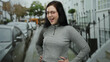 © Krakenimages.com - Woman with brunette hair and glasses smiles confidently in a city street, wearing a casual grey top, with cars and buildings in the urban background.