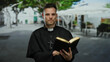 © Krakenimages.com - Priest holding book in outdoor city setting with trees and architecture captured in a vivid street scene.