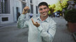 © Krakenimages.com - Young hispanic man holds car key in light blue shirt on city street while smiling at keys; excitement.