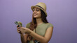 © Krakenimages.com - Young woman wearing hat counts mexican pesos on an isolated purple wall background, exuding a sense of enjoyment and travel.