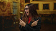 © Krakenimages.com - Woman smiling and pointing in elegant museum interior wearing glasses and blazer conveys excitement and curiosity in cultural setting indoor.