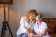 © luciano - Mature blonde woman while holding hands of her elderly mother indoors. The scene captures tenderness, affection, and emotional connection, symbolizing love, care, and companionship in later life