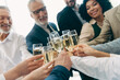© deagreez - Professional colleagues toasting with champagne glasses during a collaborative corporate celebration in a modern office
