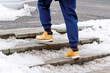 © Tricky Shark - Man in warm boots moving slowly on snowy outdoor steps, safety awareness during cold winter weather, icy conditions. Snowy staircase with man in winter footwear maintaining balance to avoid slipping