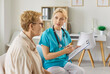 © Studio Romantic - Discussion of nurse and senior woman on doctors appointment in clinic. Professional medical worker in uniform talking, looking to elderly patient on consultation, holding clipboard with notes