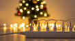 © Margarita Ratatosk - Overloaded power strip with Christmas tree lights connected to an outlet with a blurred Christmas tree in the background. Fire safety concept.