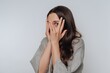 © bodnarphoto - Woman peeking through fingers with a surprised expression.