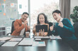 © ArLawKa - Group of successful Asian businesspeople smiling and laughing, posing and making gestures of joy together in a company office conference room.